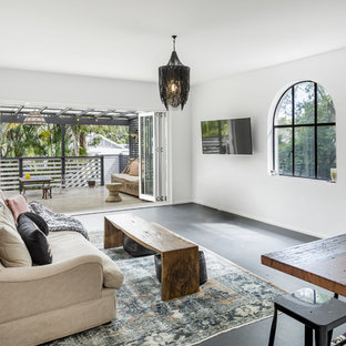 Offenes, Mittelgroßes Mediterranes Wohnzimmer mit weißer Wandfarbe, Wand-TV, schwarzem Boden und gebeiztem Holzboden in Sydney