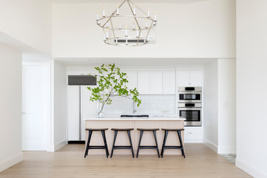 Inspiration for a mid-sized contemporary single-wall medium tone wood floor eat-in kitchen remodel in Vancouver with a double-bowl sink, shaker cabinets, medium tone wood cabinets, quartz countertops, white backsplash, ceramic backsplash, paneled appliances, an island and white countertops