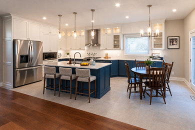 Open concept kitchen - large transitional l-shaped porcelain tile and multicolored floor open concept kitchen idea in Toronto with an undermount sink, recessed-panel cabinets, blue cabinets, quartz countertops, beige backsplash, ceramic backsplash, stainless steel appliances, an island and beige countertops