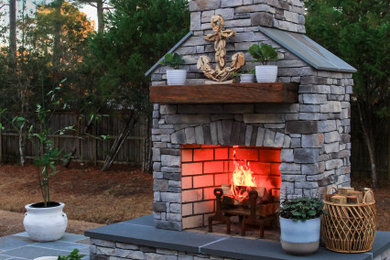 Foto de patio sin cubierta en patio trasero con chimenea y adoquines de piedra natural