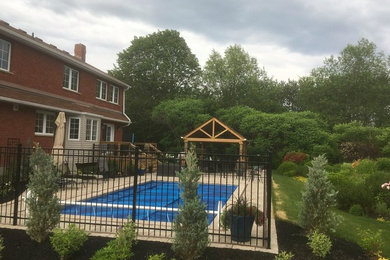 Transitional backyard patio in Toronto with natural stone pavers and a pergola.