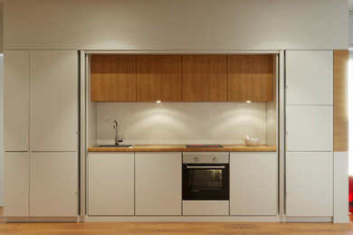 Aménagement d'une petite cuisine ouverte linéaire contemporaine avec un plan de travail en bois, une crédence blanche, une crédence en marbre et parquet clair.