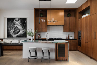 Small trendy l-shaped eat-in kitchen photo in Phoenix with an undermount sink, flat-panel cabinets, medium tone wood cabinets, quartzite countertops, white backsplash, ceramic backsplash, paneled appliances, an island and green countertops