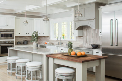 Inspiration for a transitional l-shaped kitchen in Portland Maine with a farmhouse sink, white cabinets, brown splashback, stainless steel appliances, light hardwood floors, with island, shaker cabinets and granite benchtops.