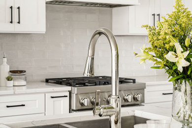 Eat-in kitchen - large transitional l-shaped eat-in kitchen idea in Charlotte with a drop-in sink, shaker cabinets, white cabinets, white backsplash, porcelain backsplash, stainless steel appliances and an island