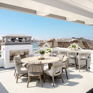 オレンジカウンティの大きいビーチスタイルのおしゃれな屋上のデッキ (屋外暖炉、張り出し屋根) の写真