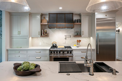 Bild på ett stort vintage vit vitt kök, med skåp i shakerstil, grå skåp, bänkskiva i kvarts, vitt stänkskydd, rostfria vitvaror, mellanmörkt trägolv, en köksö och brunt golv