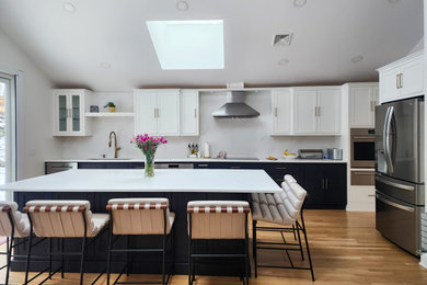 Kitchen - large transitional single-wall medium tone wood floor and vaulted ceiling kitchen idea in Boston with an undermount sink, beaded inset cabinets, blue cabinets, quartz countertops, white backsplash, quartz backsplash, stainless steel appliances, an island and white countertops