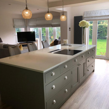 Sleek, light grey handmade kitchen with large island and white worktops