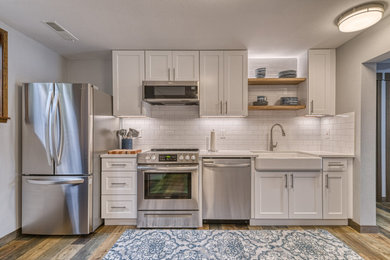 Inspiration for a mid-sized french country enclosed kitchen remodel in Seattle with a farmhouse sink, white cabinets, white backsplash, subway tile backsplash, stainless steel appliances, two islands and white countertops
