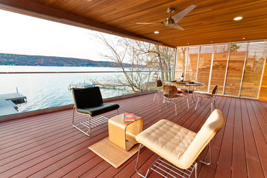Example of a large minimalist deck design in New York with a roof extension
