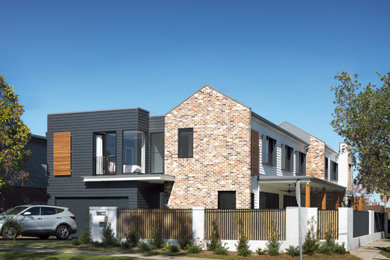 Large contemporary two-storey brick multi-coloured duplex exterior in Sydney with a gable roof and a metal roof.