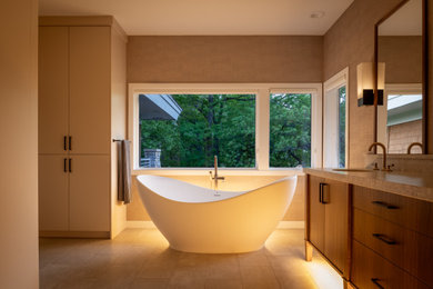 Inspiration for a mid-sized contemporary master bathroom in Minneapolis with flat-panel cabinets, medium wood cabinets, a freestanding tub, an undermount sink, granite benchtops, beige floor, an open shower, a niche, a double vanity, beige walls, ceramic floors, grey benchtops and a freestanding vanity.