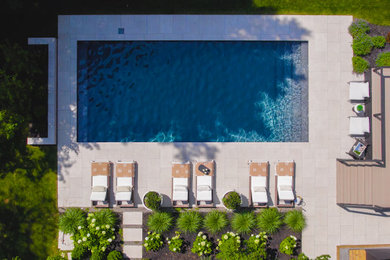 Foto de piscina tradicional renovada grande rectangular en patio trasero con paisajismo de piscina y suelo de baldosas