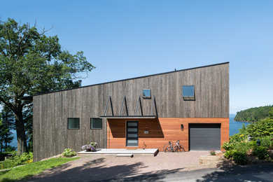 Midcentury three-storey house exterior in Other with wood siding and a shed roof.