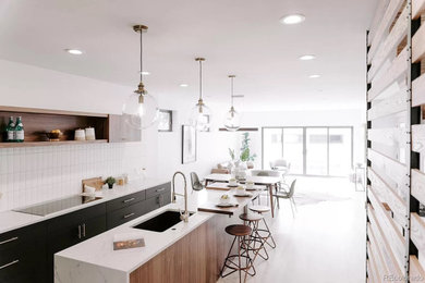 Mid-sized midcentury galley eat-in kitchen in Denver with a drop-in sink, flat-panel cabinets, black cabinets, quartz benchtops, white splashback, porcelain splashback, stainless steel appliances, with island, white benchtop, light hardwood floors and grey floor.