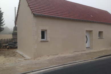 Cette photo montre une façade de maison beige nature en stuc de taille moyenne et à un étage avec un toit à deux pans.