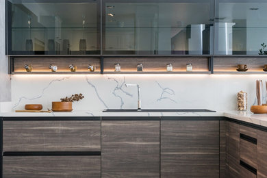 This is an example of a mid-sized modern l-shaped kitchen pantry in Los Angeles with no island, a drop-in sink, flat-panel cabinets, medium wood cabinets, marble benchtops, white splashback, marble splashback, stainless steel appliances and white benchtop.