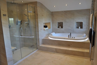Photo of a large modern master bathroom in Essex with a wall-mount sink, a drop-in tub, a curbless shower, a wall-mount toilet, beige tile, porcelain tile, beige walls and porcelain floors.