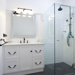 Immagine di una stanza da bagno padronale moderna di medie dimensioni con ante con riquadro incassato, ante bianche, piastrelle bianche, vasca con piedi a zampa di leone, doccia ad angolo, piastrelle di cemento, pareti bianche, lavabo sottopiano, pavimento nero e porta doccia a battente