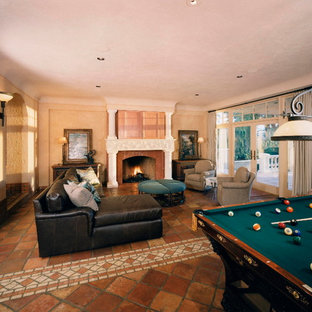 Idee per un soggiorno mediterraneo chiuso e di medie dimensioni con sala giochi, pareti beige, pavimento in terracotta, camino classico, cornice del camino in pietra e TV nascosta
