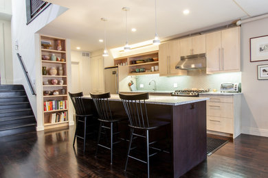 Example of a mid-sized trendy single-wall dark wood floor open concept kitchen design in New York with a single-bowl sink, flat-panel cabinets, light wood cabinets, quartz countertops, green backsplash, glass tile backsplash, stainless steel appliances and an island