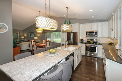 Eat-in kitchen - mid-sized transitional l-shaped dark wood floor and brown floor eat-in kitchen idea in Chicago with flat-panel cabinets, white cabinets, quartz countertops, beige backsplash, stone tile backsplash, stainless steel appliances, an island and a single-bowl sink