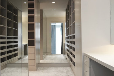 Inspiration for a contemporary carpeted walk-in closet remodel in New York with flat-panel cabinets and gray cabinets