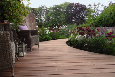 This is an example of a mid-sized country backyard garden for spring in Cheshire with a garden path and decking.
