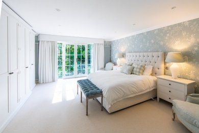 Photo of a large modern master bedroom in Surrey with blue walls, carpet, beige floors and brick walls.