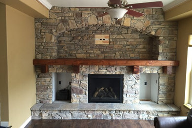 Small elegant enclosed dark wood floor family room photo in Denver with a standard fireplace, a stone fireplace and brown walls