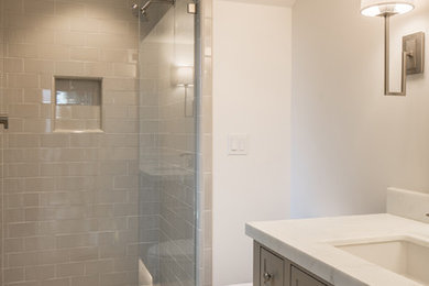 Mid-sized trendy gray tile and ceramic tile limestone floor and multicolored floor corner shower photo in San Francisco with furniture-like cabinets, gray cabinets, a one-piece toilet, white walls, an undermount sink, marble countertops, a hinged shower door and white countertops