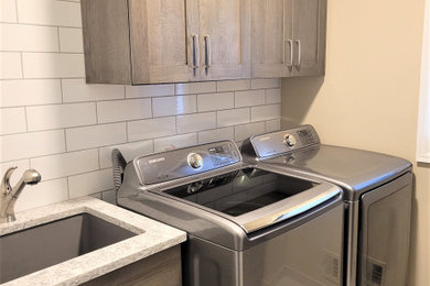 Mid-sized transitional galley porcelain tile and gray floor dedicated laundry room photo in Detroit with an undermount sink, shaker cabinets, medium tone wood cabinets, quartz countertops, white backsplash, subway tile backsplash, beige walls, a side-by-side washer/dryer and gray countertops