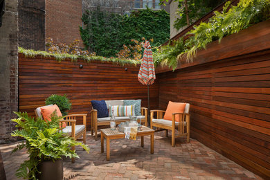 Photo of a small contemporary backyard brick landscaping in New York.