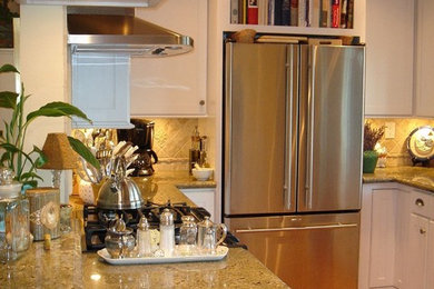 Example of a mid-sized arts and crafts u-shaped light wood floor eat-in kitchen design in San Diego with a double-bowl sink, recessed-panel cabinets, white cabinets, granite countertops, beige backsplash, stone tile backsplash, stainless steel appliances and a peninsula