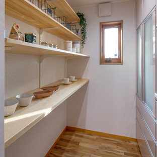 Photo of a contemporary single-wall open plan kitchen in Other with an integrated sink, flat-panel cabinets, pink cabinets, solid surface benchtops, white splashback, stainless steel appliances, medium hardwood floors, no island, beige floor, white benchtop and wallpaper.