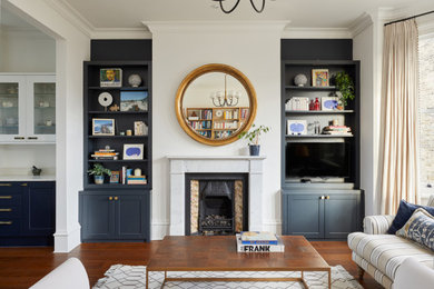 ロンドンにある高級なトランジショナルスタイルのおしゃれなLDK (白い壁、濃色無垢フローリング、標準型暖炉、石材の暖炉まわり、壁掛け型テレビ、茶色い床) の写真