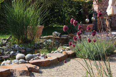 Mediterraner Kiesgarten im Sommer mit Wasserspiel und direkter Sonneneinstrahlung in Sonstige