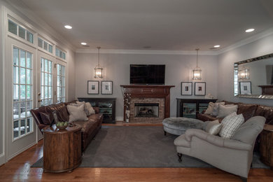 Mid-sized transitional open concept family room in Charlotte with grey walls, medium hardwood floors, a standard fireplace, a brick fireplace surround and a wall-mounted tv.