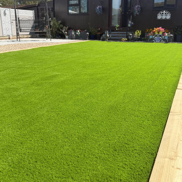 Timber Edged Artificial Lawn Beside a Dark Clad Home