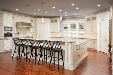 Inspiration for a large transitional u-shaped medium tone wood floor open concept kitchen remodel in Columbus with shaker cabinets, white cabinets, marble countertops, white backsplash, subway tile backsplash, stainless steel appliances and an island