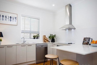 Inspiration for a small scandinavian u-shaped eat-in kitchen in Newcastle - Maitland with a drop-in sink, beige cabinets, quartzite benchtops, white splashback, subway tile splashback, stainless steel appliances, light hardwood floors, with island and brown floor.