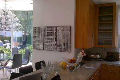 Example of a large trendy limestone floor eat-in kitchen design in Los Angeles with an undermount sink, flat-panel cabinets, medium tone wood cabinets, granite countertops, beige backsplash, stone slab backsplash, stainless steel appliances and an island