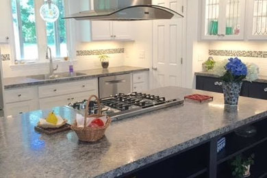 Inspiration for a vinyl floor kitchen remodel in New York with an integrated sink, shaker cabinets, white cabinets, laminate countertops, white backsplash, ceramic backsplash, stainless steel appliances and an island