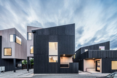 Ejemplo de fachada de casa negra y negra minimalista de tamaño medio con revestimiento de madera, tejado a dos aguas y tejado de varios materiales