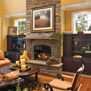 Imagen de salón para visitas abierto, mediterráneo, de tamaño medio, sin televisor, con paredes amarillas, suelo de madera oscura, chimenea tradicional y marco de chimenea de piedra