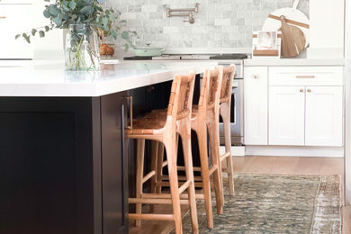 Inspiration for a large transitional u-shaped medium tone wood floor, brown floor and vaulted ceiling eat-in kitchen remodel in San Francisco with a farmhouse sink, shaker cabinets, white cabinets, quartzite countertops, stainless steel appliances, an island and white countertops