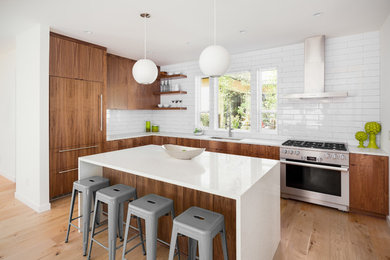 Mid-sized contemporary l-shaped eat-in kitchen in DC Metro with an undermount sink, flat-panel cabinets, medium wood cabinets, quartz benchtops, white splashback, subway tile splashback, stainless steel appliances, light hardwood floors, with island, brown floor and white benchtop.