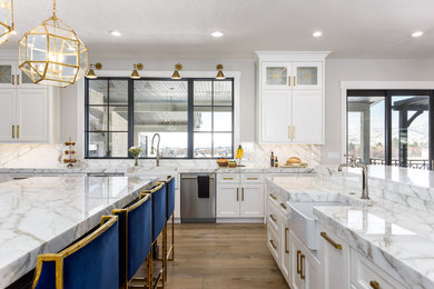 Inspiration for a large transitional single-wall separate kitchen in Salt Lake City with a farmhouse sink, shaker cabinets, white cabinets, marble benchtops, grey splashback, marble splashback, stainless steel appliances, medium hardwood floors, multiple islands, brown floor and grey benchtop.