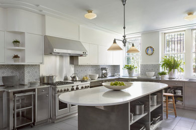 Inspiration for a large transitional u-shaped porcelain tile and gray floor enclosed kitchen remodel in New York with an integrated sink, flat-panel cabinets, white cabinets, stainless steel countertops, multicolored backsplash, cement tile backsplash, stainless steel appliances, an island and gray countertops